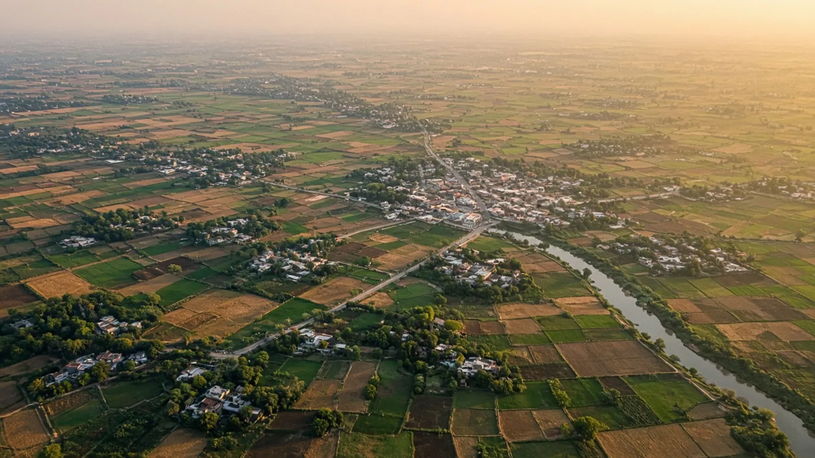 Aerial view at sunset of villages linked by roads and a river among farm plots
